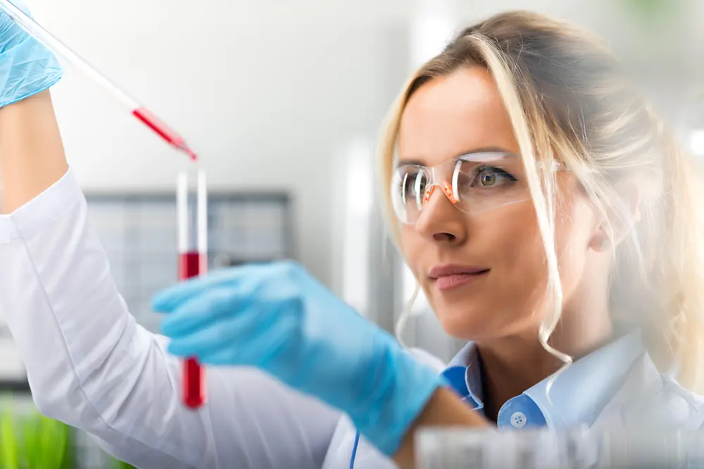 A lady is standing at the laboratory hood is working with a pipette, representing our analytical topics at Corporate Scientific Services.